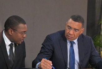 Prime Minister, Dr. the Most Hon. Andrew Holness (right), points out something in a document to Minister without Portfolio in the Ministry of Economic Growth and Job Creation, Hon. Robert Morgan, at the contract-signing ceremony for the Shared Prosperity through Accelerated Improvement to our Road Network (SPARK) Programme held at the Office of the Prime Minister on Thursday (December 5).

