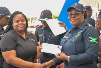 Deputy Superintendent of Police, Paulett Baker (right), receives a cheque from Manager of the Citidental and Implant Center, Venessa Morris, in support of the St. Catherine South Division’s annual Christmas initiative dubbed: ‘SHOP WITH A COP’ (SWAC) on Friday (December 20) at the Greater Portmore Police Station.

