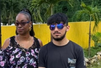 Administrator at the St. Ann Municipal Corporation, Suzette Prince, and 18-year-old-student philanthropist, Aryan Lakhwani, stand outside the Ocho Rios Drop-in-Centre in St. Ann, on Christmas Eve, December 24, during a visit to deliver food and refreshments to the needy.  