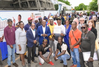 Minister of Labour and Social Security, Hon. Pearnel Charles Jr. (second row, fourth left); State Minister, Dr. the Hon. Norman Dunn (second row, third left); Ministry officials and representatives from the Canadian High Commission, share a photo opportunity with 96 farm workers before their departure to Canada on Friday (January 3), under the Seasonal Agricultural Workers Programme (SAWP). Veteran farm worker, Victor Lettman, is pictured holding a certificate. The occasion was a send-off ceremony held at the Ministry’s Overseas Employment Centre in Kingston.

