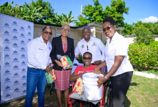 Minister of Labour and Social Security, Hon. Pearnel Charles Jr. (second right), is joined by (from left), Minister of State in the Ministry, Dr. the Hon. Norman Dunn; Member of Parliament for St. Andrew Eastern, Hon. Fayval Williams; and Executive Director of the Jamaica Council for Persons with Disabilities (JCPD), Dr. Christine Hendricks, in making a presentation to resident of Cheshire Village, St. Andrew, Sophia Johnson. Occasion was the distribution of care packages to residents of the community, which houses persons with disabilities on Tuesday (Dec. 31).