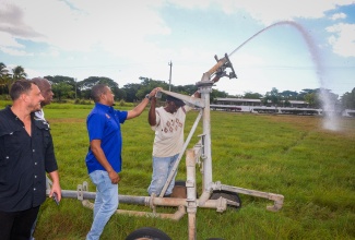 Agriculture, Fisheries and Mining Minister, Hon. Floyd Green (second right), assists a worker to activate the pump system for one of seven additional irrigation travellers acquired for the Bodles Agriculture Research Station in St. Catherine. The equipment, acquired at a cost of approximately $35.37 million, was handed over during a ceremony at Bodles on Wednesday (January 29). Looking on (from left) are Chief Executive Officer, Isratech Jamaica Limited, Benjamin Hodara; and State Minister in the Agriculture Ministry,  Hon. Franklin Witter.


