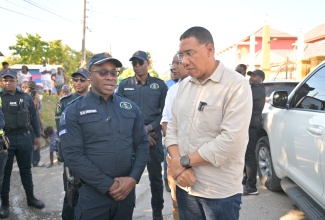 Prime Minister, Dr. the Most Hon. Andrew Holness (right), receives an update on crime fighting in Westmoreland from Commanding Officer of the Division, Superintendent Othneil Dobson, during a visit to the parish on Friday (Jan. 24), to hand over housing units under the New Social Housing Programme (NSHP).