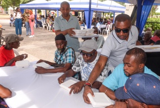 Mayor of Kingston, Councillor Andrew Swaby (third right), and Deputy Mayor of Kingston and Councillor for the Seivwright Gardens Division, Delroy Williams (second left), serve lunches during the Mayor’s annual New Year’s Day Feeding of the Homeless on New Year’s Day, January 1, 2025, at St. William Grant Park in downtown Kingston.