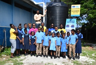 Mayor of Montego Bay, Councillor Richard Vernon (in background), proudly points to the water tank installed at the Salt Spring Primary and Infant School in St. James as part of a rainwater project implemented by the community’s Bloomberg Youth Climate Action Fund Programme group. Also sharing in the moment are (from left) Salt Spring Community Development Committee (CDC) Public Relations Officer, Sherrikay Morris, and Treasurer, Toshane Evans; Principal of the Salt Spring Primary and Infant School, Norma Brydson; Project Manager of the Bloomberg Youth Climate Action Fund, Joan Dove; Bloomberg Youth Climate Action Fund Programme group member, Kiran Beadle, and Group Project Leader, Clifton Ellis. They are flanked by students of the school. The occasion formed part of a visit by Mayor Vernon of climate resilient projects undertaken by youth groups in various communities across the parish on January 14.

