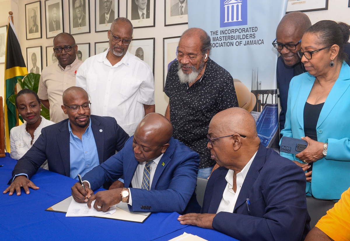 Minister of Labour and Social Security, Hon. Pearnel Charles Jr. (seated, second right), affixes his signature, as a witness, to the 2025-2027 Joint Industrial Council (JIC) Labour Management Agreement for the building and construction industry, at the Incorporated Master Builders Association of Jamaica (IMAJ) in Kingston on Tuesday (February 11). He is flanked by IMAJ President, Richard Mullings (seated, second left) and First Vice President, Dahlia Alert (seated, left); and Bustamante Industrial Trade Union (BITU) Vice President, Alden Brown (seated, right). Looking on (from left, standing) are IMAJ Second Vice President, Paul Williams; IMAJ Past Presidents Raymond Cooper, Carvel Stewart and Lenworth Kelly, and IMAJ Secretary/Manager Jacqueline Scott.  

