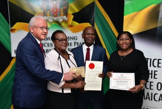 Justice Minister, Hon. Delroy Chuck (left), presents newly commissioned Justice of the Peace (JP), Elaine Antwine, with her seal of office during the swearing-in ceremony for 120 JPs for the parish of Kingston on Thursday (February 6). The ceremony was held of the Office of the Custos Rotulorum, Hon. Steadman Fuller (second right), in downtown Kingston. At right is High Court Judge, Hon. Sonia Bertram-Linton.

