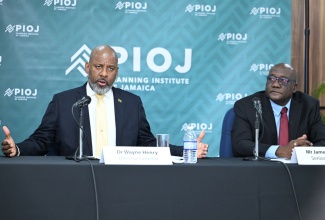 Director General of the Planning Institute of Jamaica (PIOJ), Dr. Wayne Henry (left), points out that the island is not in a recession, during a press briefing at the Don Mills Training Room, PIOJ, 16 Oxford Road, on Wednesday (February 19). He is joined by Senior Director at the PIOJ, James Stewart (right).

