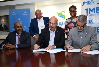 Minister of Industry, Investment and Commerce, Senator the Hon. Aubyn Hill (left), looks on as President and Chief Executive Officer (CEO) of Sagicor Group Jamaica, Christopher Zacca (seated centre) and President of the Jamaica Manufacturers and Exporters Association (JMEA), Sydney Thwaites (seated right) sign a Memorandum of Understanding (MOU) between Sagicor Life and the (JMEA) during a ceremony held at the Sagicor Group Jamaica Head Office in Kingston on Tuesday (February 25). Looking on  (standing, left) are Chief Revenue Officer at Sagicor, Mark Chisholm and Executive Director of JMEA, Kamesha Blake.

