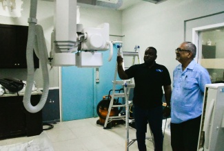 Clinical Coordinator at the Cornwall Regional Hospital (CRH) in St. James, Dr. Delroy Fray (right), listens as Radiology Manager at the facility, Stewart Lawrence, explains the features on one of two brand new X-ray machines being put in place at the hospital by the Western Regional Health Authority (WRHA).