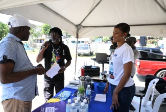 Customer Relations Manager for National Water Commission (NWC), St. Thomas, Calvert Harrison (left), and Acting Community Relations Manager for the NWC’s Northeast division, Ann Bolt (centre), speak with a customer during a recent public engagement in Morant Bay.

