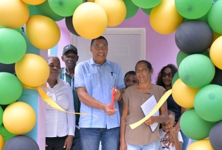 Prime Minister, Dr. the Most Hon. Andrew Holness (centre), cuts the ribbon to officially handover a two-bedroom house to New Social Housing Programme (NSHP) beneficiary, Esther McKenzie during a ceremony held in New Market, St. Elizabeth on Friday (March 14). Also participating are (from left) Chairperson of the NSHP Oversight Committee, Judith Robb Walters; Minister of State in the Ministry of Science, Energy, Telecommunications and Transport and Member of Parliament for St. Elizabeth Northeastern, Hon. JC Hutchinson; Ms. McKenzie’s grandson, Tarique Wright; her daughter Kassandra Wright and grandson, Romani Whyte.