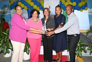 Permanent Secretary in the Ministry of Industry, Investment and Commerce, Sancia Bennett Templer (centre), hands over an award to staff of Seaboard Freight and Shipping for 23 years of service in the Montego Bay Free Zone (MBFZ), during a 40th Anniversary Client Awards Ceremony, in St. James, on Thursday (March 27). The staff include (from left) Branch and Warehouse Manager, Eleanor Williams; CEO, Corah-Ann Robertson-Sylvester; Sales Executive, Abigail Williams; and Warehouse Supervisor, Troy Manderson.