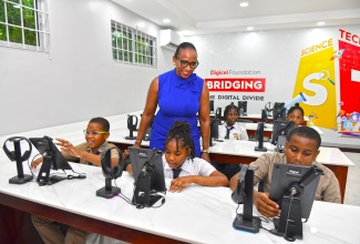 Chairman of the Digicel Foundation, Joy Clarke (centre), observes as students from St. Jude’s Primary School use the computers in the smart laboratory, which was officially handed over to the institution in St. Andrew on Tuesday (March 25). The laboratory, established by the Digicel Foundation, is equipped with 24 computers, an interactive smart board, a printer, a smart door lock for safety and Digicel’s high-speed Internet connectivity.

