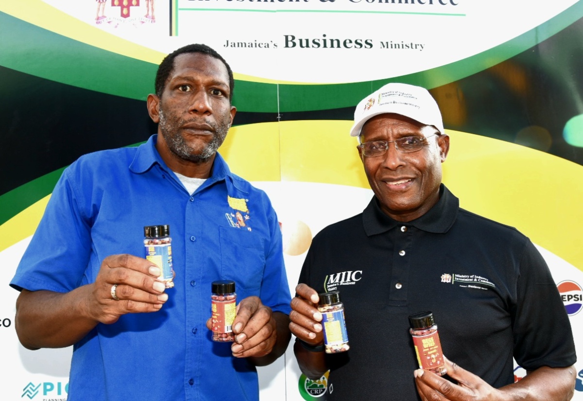 Minister of Industry, Investment and Commerce, Senator the Hon. Aubyn Hill (right), and Chief Executive Officer (CEO) of Bess Bites, Marlon Ledgister, show off the company’s baked peanut product, during the MSME Business Roadshow at the St. Elizabeth Technical High School (STETHS) in Santa Cruz on Thursday, March 6.

