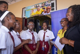 Director of Communications and Public Relations at the Ministry of Education, Skills, Youth and Information, Ruth Ann Carr (right), and Corrine Duffus from the Communication and Public Relations Division, interact with Glenmuir High School students at the inaugural Region 7 Mathematics Day Extravaganza held at the institution in May Pen, Clarendon on Friday (March 28). The event was held under the theme: ‘Innovating for Tomorrow: Empowering Future Leaders Through STEAM.’