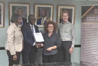 Minister of Labour and Social Security, Hon. Pearnel Charles Jr. (second left), and Consultant on the Strengthening the Public Investment in Labour Market Services (SPIRO) Project, Mrs. Ada Shima Hasani (second right), display a contract signed during a ceremony held at the Ministry’s North Street office in Kingston on Friday (February 28). Others (from left) are Acting Permanent Secretary in the Ministry, Dione Jennings and consultant, SPIRO Project, Trond Henning Olesen.