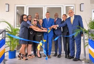 Prime Minister, Dr. the Most Hon. Andrew Holness (fourth right), cuts the ribbon symbolising the official opening of The Nitrams of Waterloo, located at 44 Upper Waterloo Road in St. Andrew, on March 25. He is joined by (from left, front row): daughters of developer of The Nitrams of Waterloo, the late Philip Martin and directors of Nitram Developments Limited, Wendy Martin Haddad; Kathy Greaux; Anna-Kaye Martin-Shirley; General Manager, Jamaica Mortgage Bank, Courtney Wynter; Senior Vice President, Corporate Banking and SME Business Banking, Sagicor Bank Jamaica, Michael Willacy; Minister of Justice and Member of Parliament, St. Andrew North Eastern, Hon. Delroy Chuck. Also at the opening are (second row): Director, Business Operation, Jamaica Mortgage Bank, Patricia Burke; and Acting Chairman, Jamaica Mortgage Bank, Ryan Parkes.

