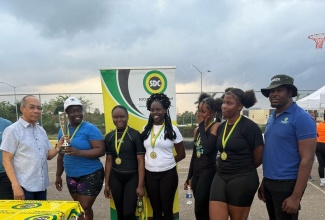 Deputy Prime Minister, Minister of National Security and Member of Parliament for St. James North Western, Hon. Dr. Horace Chang (left), presents the Social Development Commission’s (SDC) Flankers Netball Competition winner’s trophy to members of Pelle Drive. At right is SDC Community Facilitator, Warren Morle.