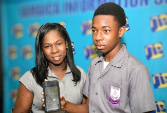 Student at Decarteret High School in Mandeville, Manchester, Joel Campbell (right), demonstrates the functions of the Study Smart Artificial Intelligence (AI) Tutor for the Caribbean Examinations Council (CXC AI Tutor) technology, developed by EduHub Company Limited, during Tuesday’s (April 22) Jamaica Information Service (JIS) Think Tank. At left is EduHub’s Chief Executive Officer, Davia Bryan-Campbell, who spoke during the Think Tank.

