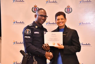 Head of the St. James Police Division, Senior Superintendent Eron Samuels (left), receives his certificate of completion from Senior Corporate Director of the Sandals Corporate University (SCU) , Dr. Luz Longsworth. Mr. Samuels was among some 210 police officers who were awarded certificates for completing SCU’s Leadership Training Initiative. Occasion was the certificate presentation ceremony for the programme, held recently at Sandals Montego Bay in St. James.

