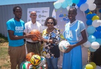 Minister of Culture, Gender, Entertainment and Sport, Hon. Olivia Grange (second right), hands over a bag containing sports balls to student at the Greater Portmore High School, Milton Peynado (left). Sharing the moment are General Manager of the Sports Development Fund (SDF), Alan Beckford (second left) and fellow student, Natalia Smith. Occasion was the recent official hand over of two renovated multipurpose courts at the institution in St. Catherine.