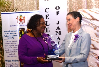 Minister of Culture, Gender, Entertainment and Sport, Hon. Olivia Grange (left), makes a presentation to Minister of Foreign Affairs and Foreign Trade, Senator the Hon. Kamina Johnson Smith, in recognition of her pioneering role as the first female Foreign Minister. Occasion was an International Women’s Day (IWD) event, held recently at the Jamaica Pegasus Hotel in New Kingston.