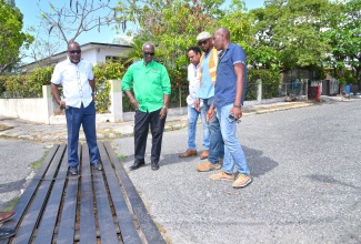 Minister of Local Government and Community Development, Hon. Desmond McKenzie (second left), looks at a drain in Arizona Avenue in Portmore, St. Catherine, during a site visit to the community on Tuesday (April 22), to get a first-hand look at drain issues impacting residents.  Looking on are (from left) Mayor of Portmore, Leon Thomas; Chief Technical Director in the Ministry, Dwight Wilson; Assistant Parish Manager for National Works Agency (NWA), St. Catherine, Courtney Mullings; and Councillor for the Independence City Division, Courtney Edwards.