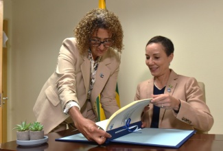 Minister of Foreign Affairs & Foreign Trade, Senator the Hon. Kamina Johnson Smith (right), is assisted by Assistant Secretary-General for Foreign and Community Relations at CARICOM, Elizabeth Solomon, during the signing ceremony for the Protocol to Amend the Revised Treaty of Chaguaramas, at the Ministry in downtown Kingston on April 3. The agreement will allow for enhanced cooperation among CARICOM Member States.