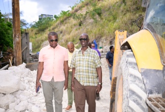 Minister of Local Government and Community Development, Hon. Desmond McKenzie (right) and Mayor of Kingston, Councillor Andrew Swaby (left) tour a section of the Tavistock roadway in St. Andrew where emergency repair work is being carried out to fix a breakaway. The Minister and his team visited the location on Friday (April 4).