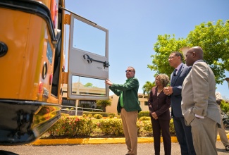 Prime Minister, Dr. the Most Hon. Andrew Holness (second right), looks on as Science, Energy, Telecommunications and Transport Minister, Hon. Daryl Vaz (left), demonstrates the use of the emergency exit door in one of the buses to be utilised in the dedicated school bus system. Also observing are Education, Skills, Youth and Information Minister, Dr. the Hon. Dana Morris Dixon; and Industry, Investment and Commerce Minister, Senator the Hon. Aubyn Hill (right). The Prime Minister was conducting a tour of the retrofitted unit on Monday (April 7), at the Office of the Prime Minister (OPM) in Kingston


