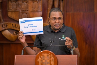 Minister without Portfolio in the Ministry of Economic Growth and Job Creation with responsibility for Works, Hon. Robert Morgan, displays a copy of a Shared Prosperity Through Accelerated Improvement to Our Road Network (SPARK) Programme progress report, as he addresses Wednesday’s (April 30) post-Cabinet press briefing at Jamaica House.