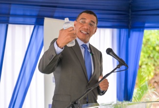 Prime Minister, Dr. the Most Hon. Andrew Holness, savours a sip of water while delivering the keynote address during the commissioning of phase one of the Rhyne Park Water Supply Improvement Project at Barrett Town All Age School in St. James on Thursday (April 10).
