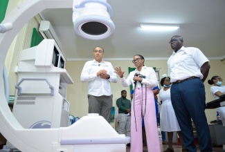 Minister of Health and Wellness, Dr. the Hon. Christopher Tufton (left), and Chief Executive Officer of the Liguanea Region of Hospitals, Dwayne Francis, observe as Senior Medical Officer at the National Chest Hospital in Kingston, Dr. Terry Baker, explains the functions of the C-ARM fluoroscopy machine which is used to facilitate surgeries at the institution. Dr. Tufton toured the hospital on Thursday (May 15).

