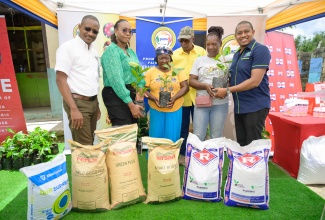 Minister of Agriculture, Fisheries and Mining, Hon. Floyd Green (right), presents seedlings to Marcia Nelson (second right) and Lurline Grant (centre) during the handover of key agricultural inputs to St. Andrew East Rural coffee farmers at Resource Square in Cinchona on Tuesday (May 20). Sharing in the occasion are Director General (Acting) at the Jamaica Agricultural Commodities Regulatory Authority (JACRA), Wayne Hunter (left);  Speaker of the House of Representatives and Member of Parliament for St. Andrew East Rural, the Most Hon. Juliet Holness (second left); and President of the Jamaica Coffee Growers’ Association (JACRA), Donald Salmon (background).