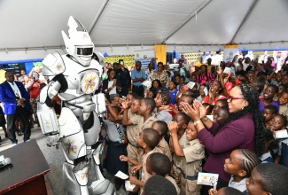 Permanent Secretary in the Ministry of Education, Skills, Youth and Information, Dr. Kasan Troupe (right), applauds as the Captain I Can robot engages with schoolchildren at the launch of the Captain I Can School Tour, under the theme 
