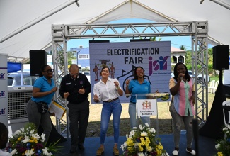 General Manager, Finance, Procurement and Standards at the Jamaica Social Investment Fund (JSIF), Orville Hill (second left), and Member of Parliament for Portland East, Ann-Marie Vaz (centre), amp up the energy at an Electrification Fair in Port Antonio, on April 24. 


