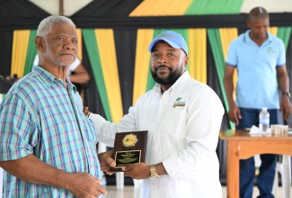 Chief Executive Officer of the Coconut Industry Board, Shaun Cameron (right), presents an award to coconut farmer Rainford Heslop, during Town Hall Meeting in Morant Bay, St. Thomas, on May 27.

