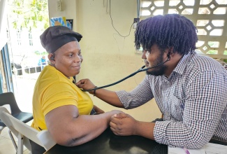 Volunteer from Great Shape! Inc. 1000 Smiles, Dr. Delano Dean, conducts a health check on resident Nicole McDermott, during the organisation’s recent Health Fair Extravaganza at Boscobel Primary and Infant School in St. Mary.

