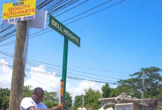Councillor for the Ensom City Division, Yacob Cookhorn  (left) and residents install a street sign in Bell Heights along Gordon Boulevard, during Labour Day activities in Gordon Pen, St. Catherine on Friday (May 23).