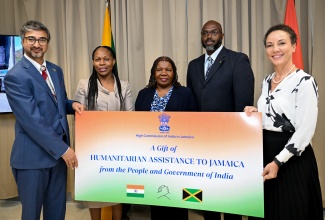 Commissioner of India to Jamaica, His Excellency Shri Mayank Joshi (left), makes a symbolic presentation to Minister of Foreign Affairs and Foreign Trade, Senator the Hon. Kamina Johnson Smith (right), during the handover ceremony for humanitarian and medical supplies from the Republic of India, at the Ministry of Foreign Affairs and Foreign Trade in downtown Kingston, on Thursday (May 1). Also sharing the moment ( from second left) are Permanent Secretary in the Ministry of Local Government and Community Development, Marsha Henry-Martin; Chief Technical Director at the Ministry, Ambassador Sharon Miller and Director General at the Office of Disaster Preparedness and Emergency Management (ODPEM), Richard Thompson.