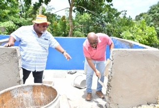 Mayor of Savanna-la-Mar, Councillor Danree Delancy (right), and Councillor for the Darliston Division, Jerome Bacchus, work on a section of the garbage skip near the Darliston Cemetery in Westmoreland, which was expanded as part of Labour Day activities in the parish on Friday ( May 23). 

