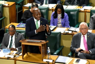 Minister of Labour and Social Security, Hon. Pearnel Charles Jr., makes his contribution to the 2025/26 Sectoral Debate in the House of Representatives on Tuesday (May 13). Listening are State Minister in the Ministry,  Dr. the Hon. Norman Dunn (left), and Minister of Justice, Hon. Delroy Chuck (right).

