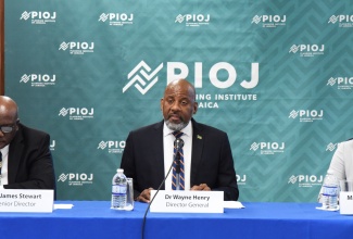 Director General, Planning Institute of Jamaica (PIOJ), Dr. Wayne Henry (centre), addresses Wednesday’s (May 21) Quarterly Press Briefing at PIOJ’s Oxford Road offices in Kingston. He is joined by (from left) Senior Director, James Stewart; and Director, Policy Research Unit, Suzette Johnson.

