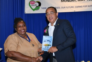 Minister of Health and Wellness, Dr. the Hon. Christopher Tufton (right), presents a copy of his book, ‘Wild Flavours’, to President of the Nurses Association of Jamaica (NAJ), Dawn Marie Richards, during today’s (May 12), observance of International Nurses Day and the launch of National Nurses’ Week, at The Jamaica Pegasus hotel in New Kingston.