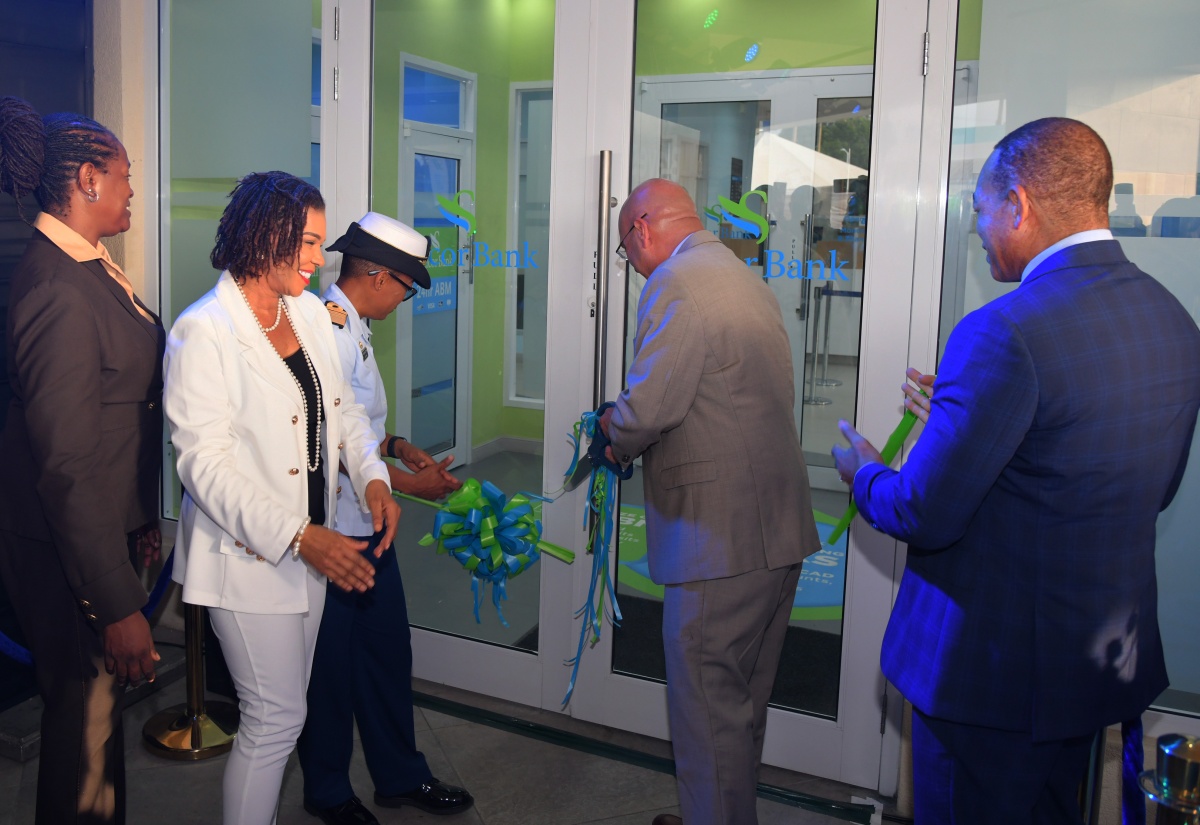 Minister of Efficiency, Innovation and Digital Transformation, Senator the Hon. Ambassador Audrey Marks (second left), observes as Sagicor Group Jamaica President and Chief Executive Officer (CEO), Christopher Zacca (second right), cuts the ribbon to officially open Sagicor Bank’s newest ‘phygital’ branch at Up Park Camp in Kingston on Tuesday (May 27). Others (from left) are Sagicor Bank CEO, Chorvelle Johnson Cunningham; Chief of Defence Staff, Vice Admiral Antonette Wemyss-Gorman;, and Senior Vice President, Corporate, Retail and Strategic Business Development, Sagicor Group, Michael Willacy.
