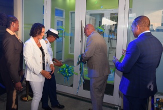 Minister of Efficiency, Innovation and Digital Transformation, Senator the Hon. Ambassador Audrey Marks (second left), observes as Sagicor Group Jamaica President and Chief Executive Officer (CEO), Christopher Zacca (second right), cuts the ribbon to officially open Sagicor Bank’s newest ‘phygital’ branch at Up Park Camp in Kingston on Tuesday (May 27). Others (from left) are Sagicor Bank CEO, Chorvelle Johnson Cunningham; Chief of Defence Staff, Vice Admiral Antonette Wemyss-Gorman;, and Senior Vice President, Corporate, Retail and Strategic Business Development, Sagicor Group, Michael Willacy.
