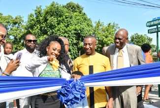 Olympian Shelly-Ann Fraser-Pryce cuts the ribbon during the ceremony for the renaming of Ashoka Road to Shelly-Ann Fraser-Pryce Drive on Sunday (May 25). Sharing the moment are Mayor of Kingston, Andrew Swaby (second right), Councillor for the Waterhouse division, Byron Clarke (right) and residents of Waterhouse.

