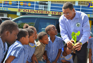 Prime Minister, Dr. the Most Hon. Andrew Holness (right), explains the importance of trees to students of the Seaward Primary and Junior High School during a National Tree Planting Day exercise at the school on Olympic Way in St Andrew.

