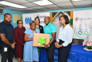 Minister of Labour and Social Security, Hon. Pearnel Charles Jr. (second right), presents a laptop to Irene Walter during a ceremony at the National Council for Senior Citizens (NCSC) office in Kingston on May 9. Mrs. Walter, 89 years old, was one of the top performers in a digital literacy course offered to senior citizens by the HEART/NSTA Trust. Sharing the moment (L-R) are Chief Executive Officer (CEO) of the Universal Service Fund (USF), Charlton McFarlane; Deputy Managing Director, National Training & Programmes Division at HEART NSTA/Trust, Dr. Cheryl McLaughlin; NCSC Chair, Dr. Julian McKoy-Davis and Permanent Secretary in the Ministry, Dione Jennings.

